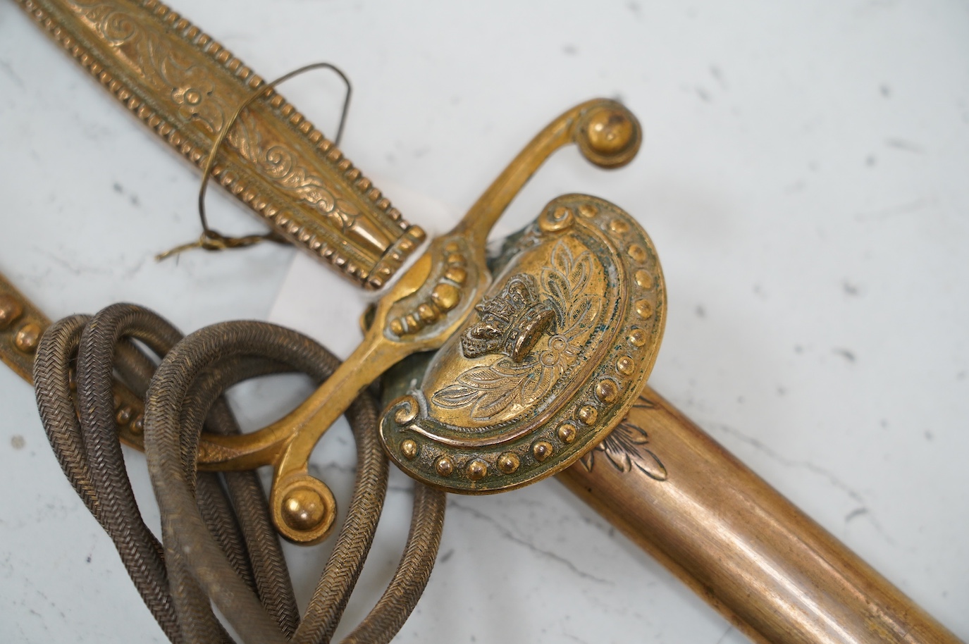 A late Victorian court sword gilt brass hilt with crown on guard, beaded edges, bullion dress knots, in its leather scabbard, blade 78cm. Condition - fair to good